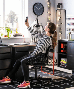Woman using red and black IKEA MICKE desks in a creative home office
