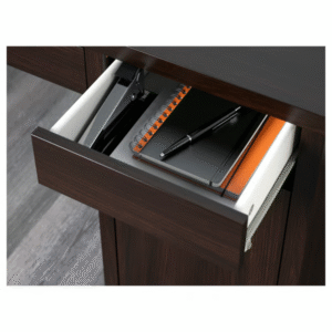Black-brown desk drawer open with notebook, stapler, and pen inside – close-up of MICKE desk