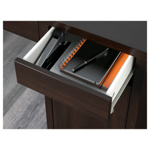 Black-brown desk drawer open with notebook, stapler, and pen inside – close-up of MICKE desk