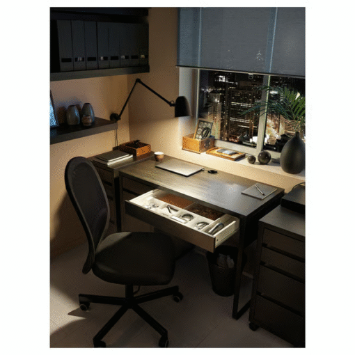 Drawer open on black-brown desk under warm light – night work setup