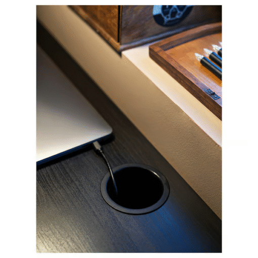 Close-up of cable outlet on black-brown desk with laptop charger